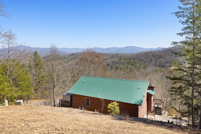 exterior space featuring a view of trees, a mountain view, and metal roof