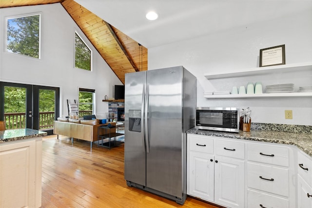 kitchen featuring white cabinetry, stainless steel appliances, wooden ceiling, dark stone counters, and light hardwood / wood-style floors