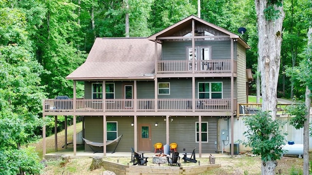 back of property with a fire pit, a patio area, and central air condition unit