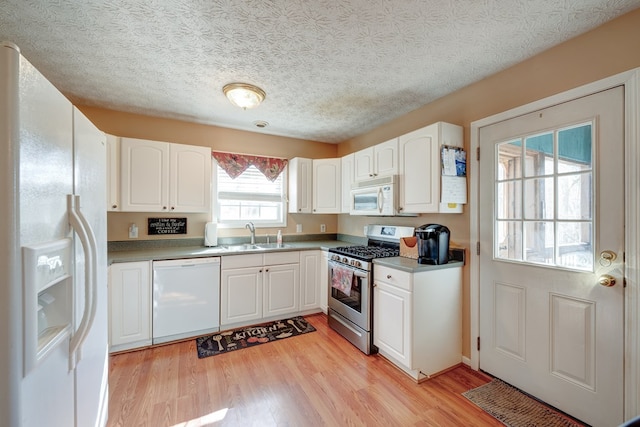 kitchen featuring white appliances, sink, a textured ceiling, light hardwood / wood-style floors, and white cabinets