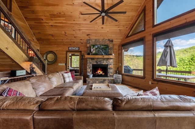 living room with wood walls, wooden ceiling, high vaulted ceiling, ceiling fan, and a fireplace