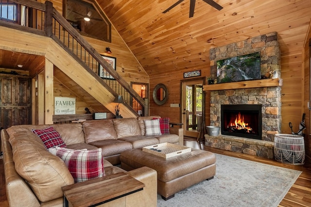 living room with wood ceiling, wood walls, hardwood / wood-style flooring, high vaulted ceiling, and a fireplace