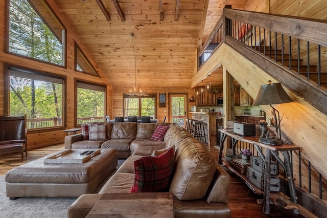 living room featuring dark wood-type flooring, wood walls, a chandelier, and plenty of natural light