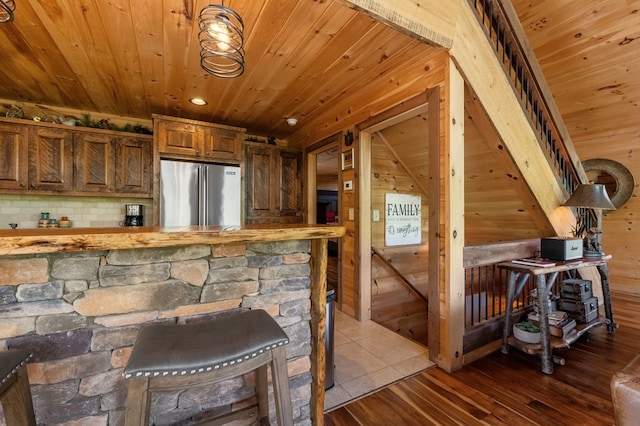 bar featuring high end refrigerator, backsplash, hardwood / wood-style floors, wood ceiling, and wooden walls