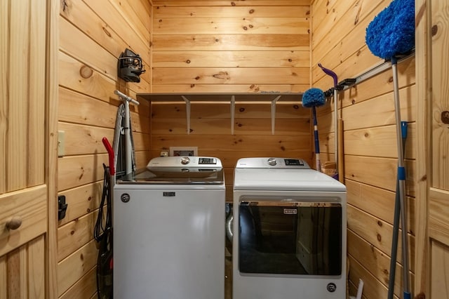 washroom with wood walls and washer and dryer