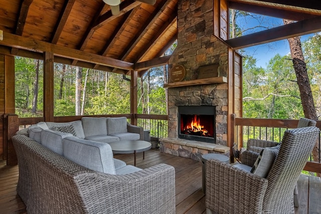 sunroom with an outdoor stone fireplace, a healthy amount of sunlight, and vaulted ceiling with beams