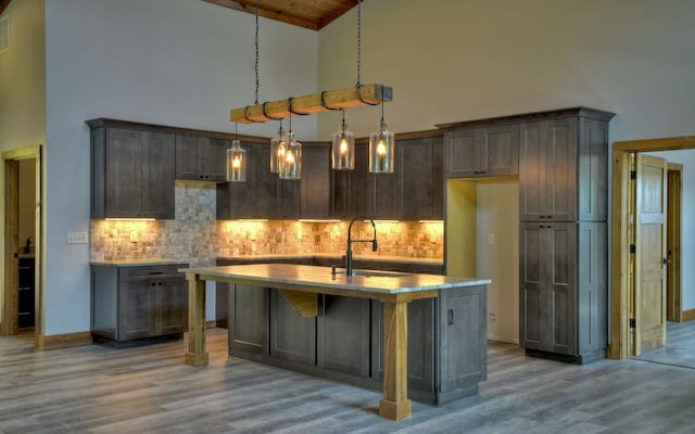 bar featuring decorative light fixtures, wood-type flooring, high vaulted ceiling, and tasteful backsplash