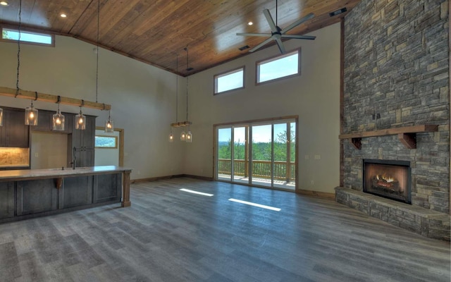 unfurnished living room featuring a stone fireplace, ceiling fan, wooden ceiling, dark wood-type flooring, and high vaulted ceiling