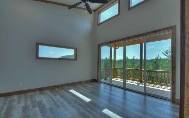 unfurnished living room with hardwood / wood-style floors, a healthy amount of sunlight, a high ceiling, and ceiling fan