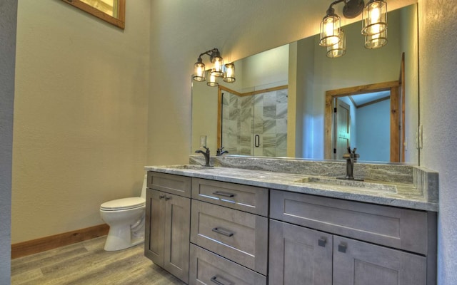 bathroom with vanity, a shower with shower door, wood-type flooring, and toilet