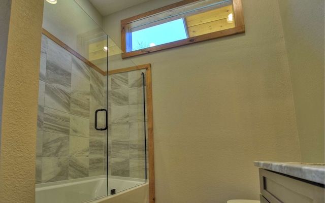 full bathroom featuring vanity, combined bath / shower with glass door, and toilet