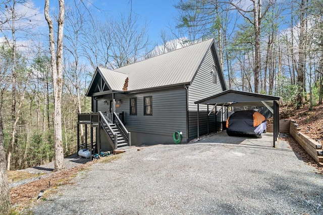 view of side of property featuring stairway, a carport, gravel driveway, and metal roof
