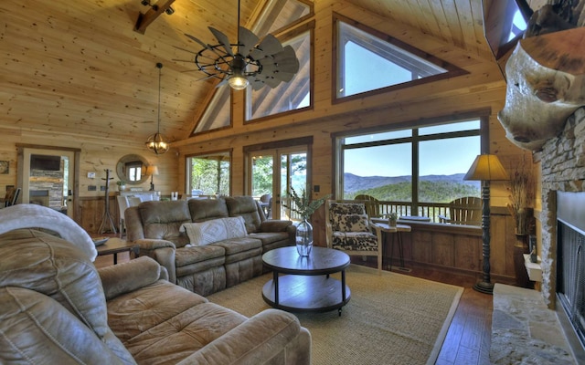 living area featuring wooden ceiling, wooden walls, a mountain view, and a stone fireplace