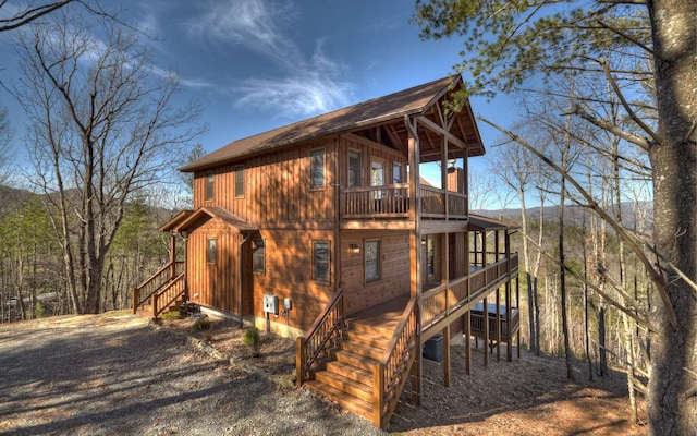 exterior space featuring driveway, stairway, cooling unit, and a balcony