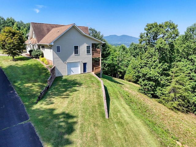 view of side of property featuring driveway, an attached garage, a lawn, and a wooden deck