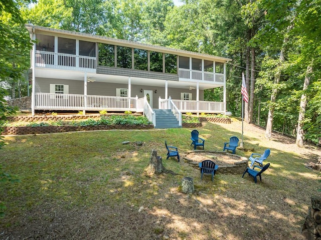 view of front facade featuring a front yard, a sunroom, and a fire pit