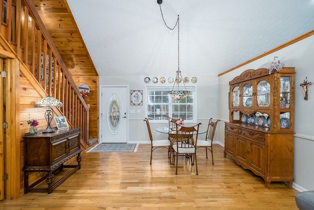 dining area featuring light wood finished floors, stairs, baseboards, and vaulted ceiling