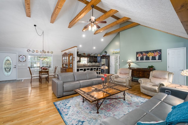 living area with light wood-style floors, beamed ceiling, high vaulted ceiling, and a ceiling fan