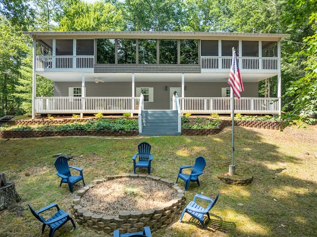 view of front facade featuring a front yard, a sunroom, and a fire pit