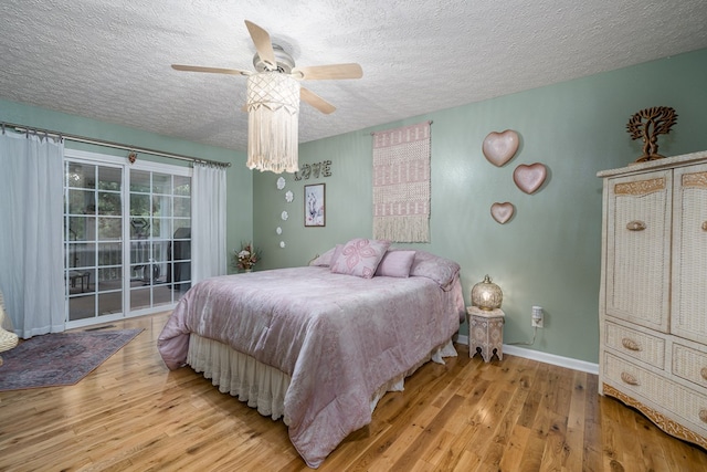 bedroom featuring a textured ceiling, access to outside, wood finished floors, and baseboards