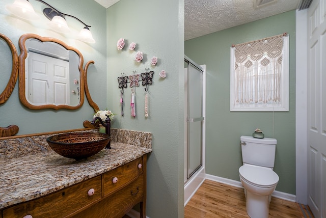 bathroom featuring toilet, an enclosed shower, vanity, a textured ceiling, and wood finished floors