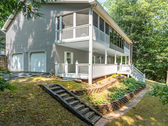 view of property exterior with an attached garage, a sunroom, stairs, and a porch