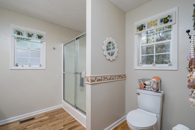 bathroom with a stall shower, a healthy amount of sunlight, visible vents, and a textured ceiling