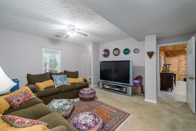 carpeted living room featuring a textured ceiling, ceiling fan, visible vents, and baseboards