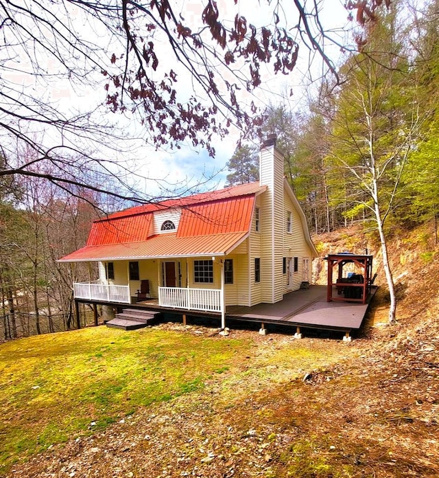 rear view of property featuring covered porch, metal roof, and a chimney