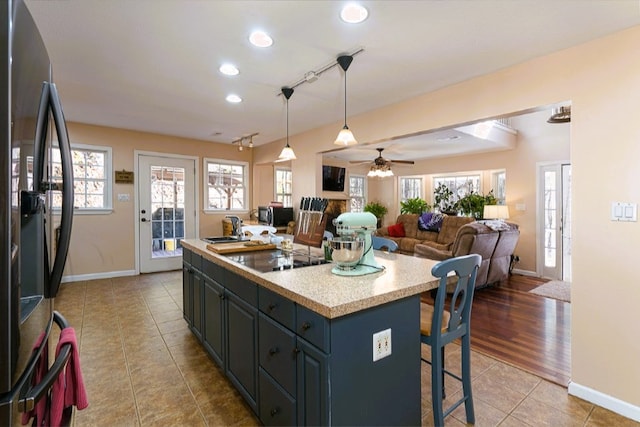 kitchen featuring tile patterned floors, baseboards, black appliances, and light countertops