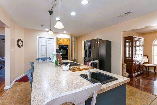 kitchen with black appliances, visible vents, light countertops, and a sink