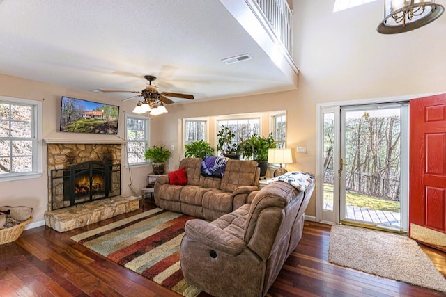 living area featuring a fireplace, visible vents, a healthy amount of sunlight, and hardwood / wood-style flooring