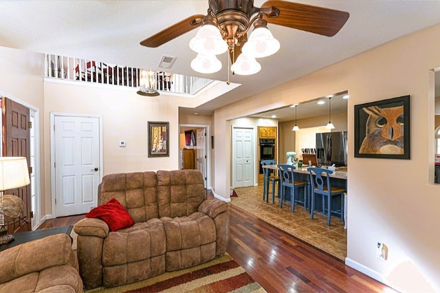 living area featuring baseboards, visible vents, a ceiling fan, and dark wood-type flooring