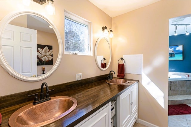 full bath with double vanity, a sink, tile patterned floors, and a tub