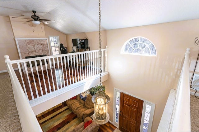 stairs with ceiling fan, a tile fireplace, and lofted ceiling
