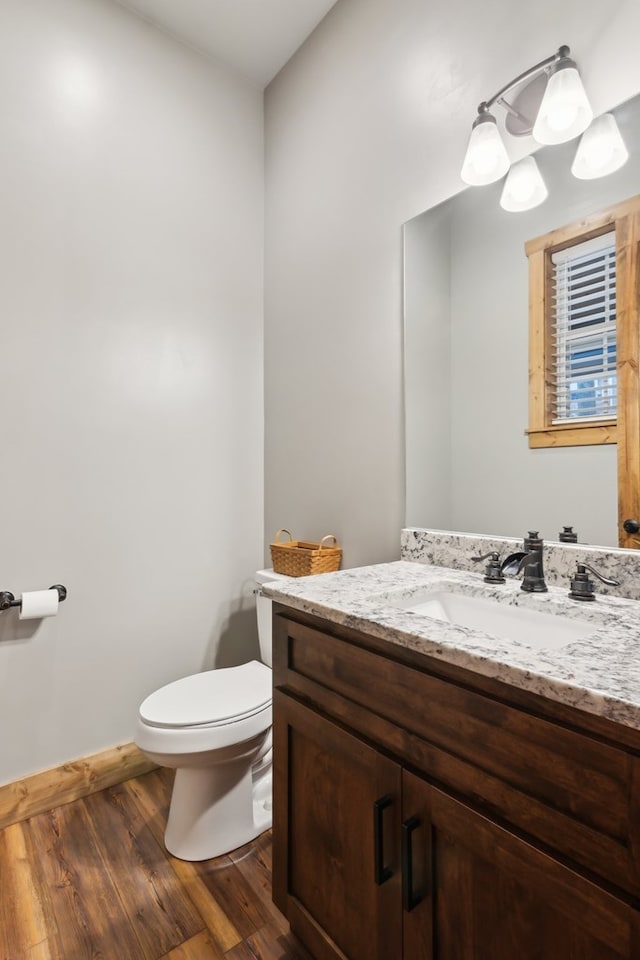 bathroom with toilet, baseboards, wood finished floors, and vanity