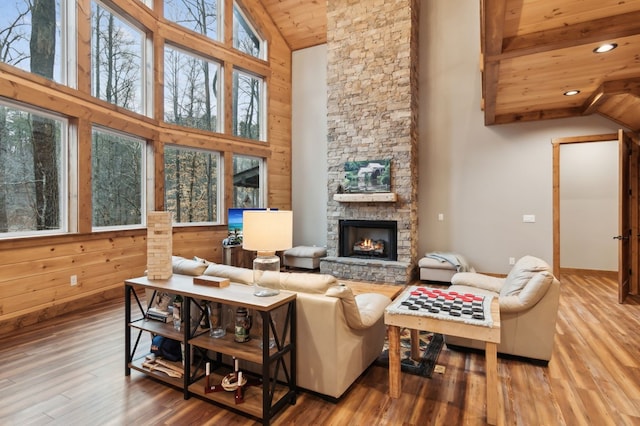 living room with a stone fireplace, wood finished floors, high vaulted ceiling, wooden ceiling, and beamed ceiling