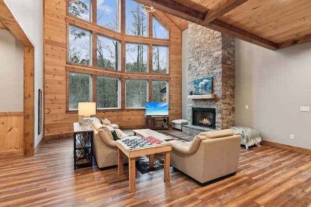 living area featuring beamed ceiling, a fireplace, wood finished floors, and wooden walls