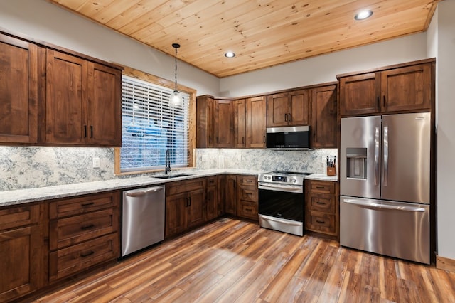 kitchen with light stone counters, decorative light fixtures, decorative backsplash, appliances with stainless steel finishes, and a sink