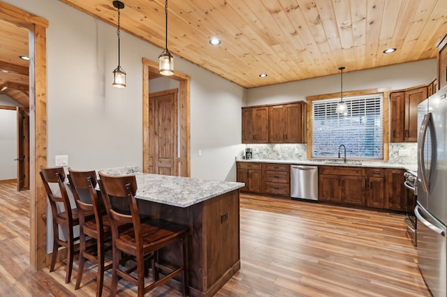 kitchen with stainless steel appliances, decorative light fixtures, a sink, and a kitchen breakfast bar