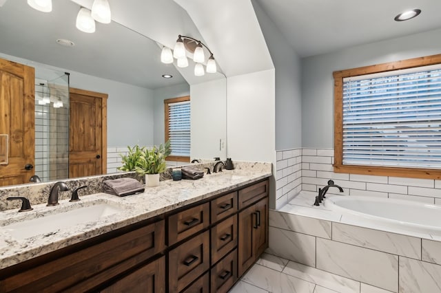 bathroom with marble finish floor, a garden tub, a sink, and double vanity