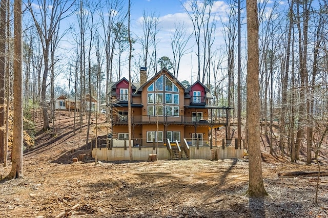 back of property with a chimney and a wooden deck