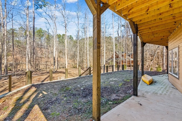 view of yard featuring a forest view, a patio area, and a fenced backyard