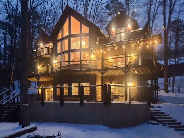 snow covered property with stairway and a balcony