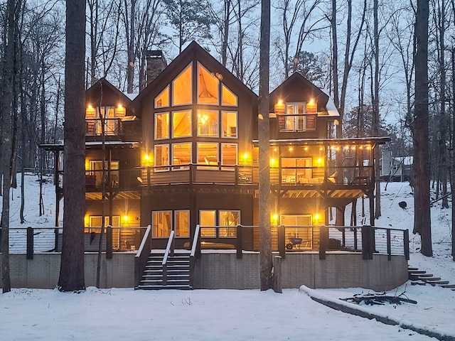 snow covered house featuring stairway, a chimney, and a balcony