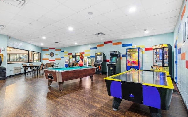 playroom with dark wood-type flooring, a paneled ceiling, and visible vents