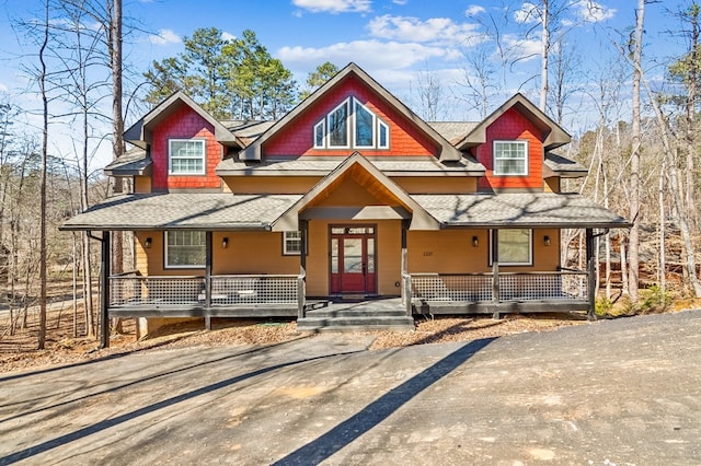 rustic home with a porch and roof with shingles