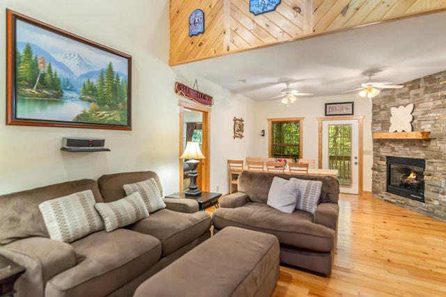 living room featuring a fireplace, ceiling fan, and light wood-type flooring