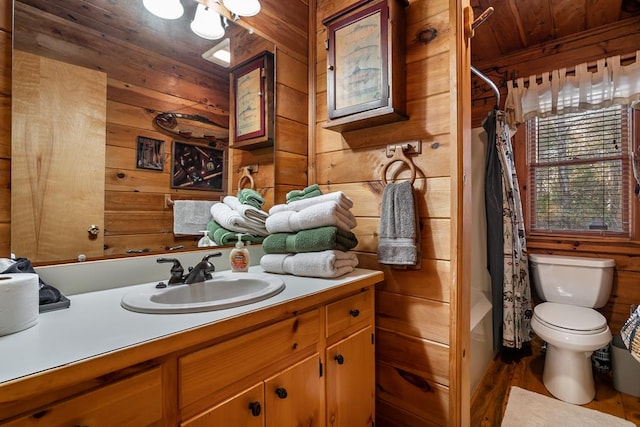 full bathroom with toilet, wood ceiling, wooden walls, and vanity