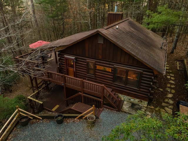 view of front of property with log exterior, a chimney, and roof with shingles